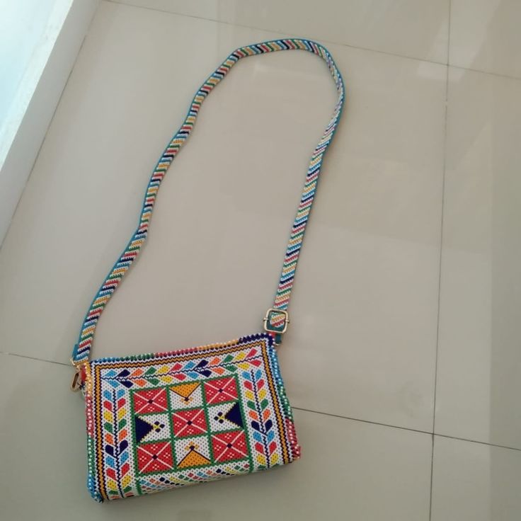 a multicolored purse sitting on top of a white tile floor next to a window