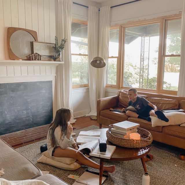 a man and woman sitting on couches in a living room next to a fireplace