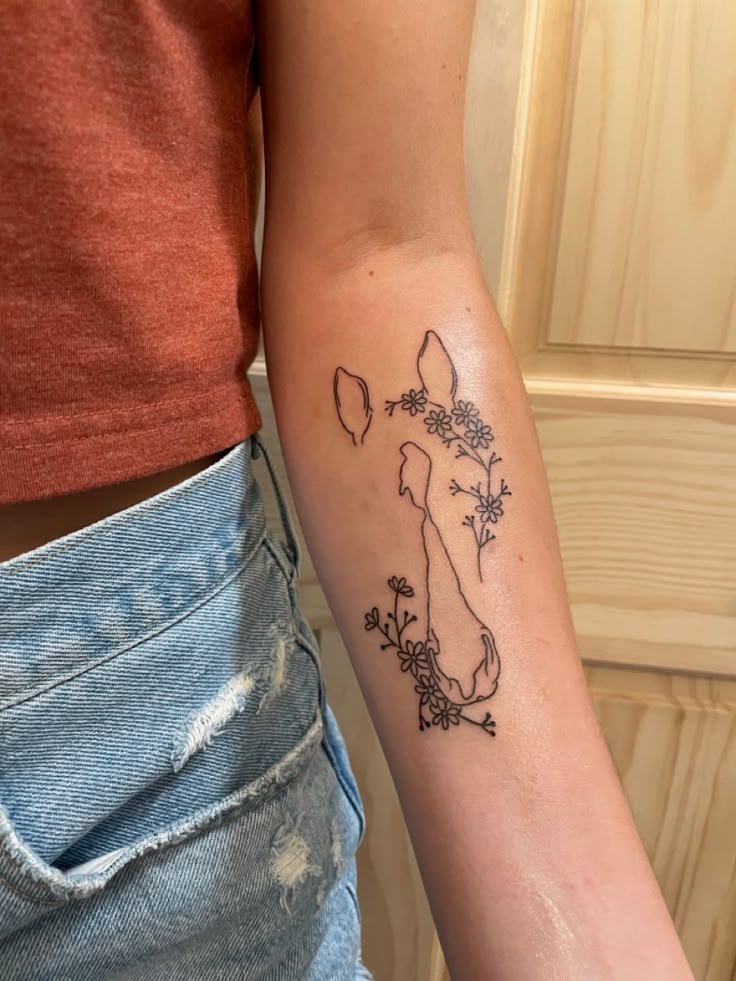 a woman's arm with a tattoo on it that has flowers in the shape of a dog