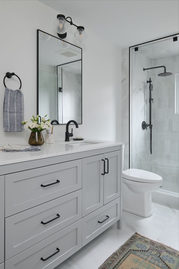 a white bathroom with two sinks and a large mirror on the wall over the toilet