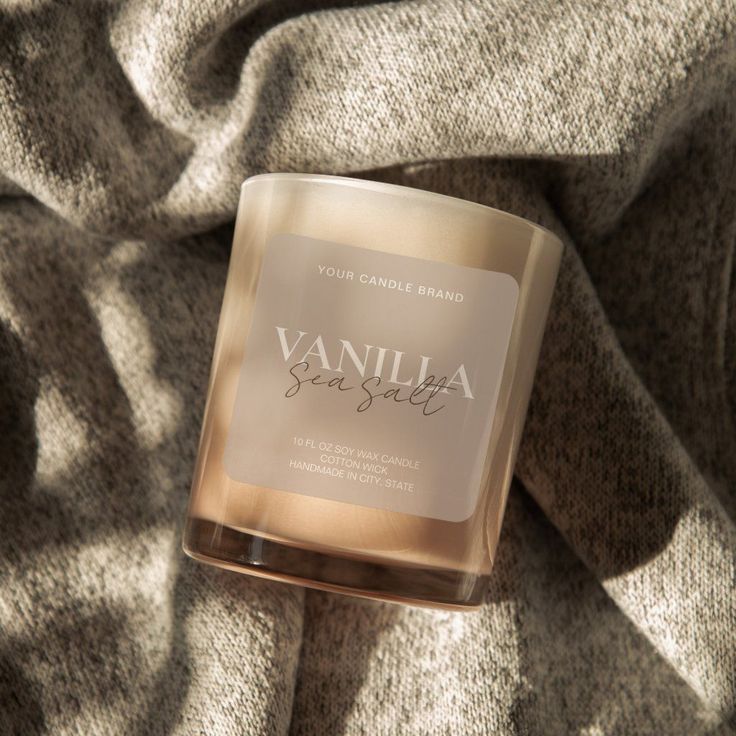 a candle that is sitting on top of a blanket with the words vanilla sea salt