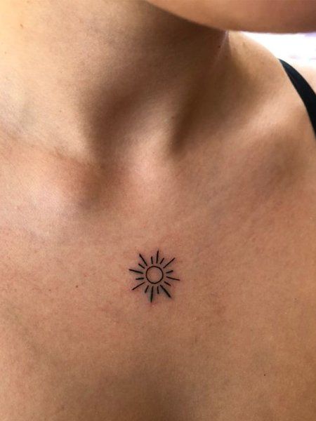 a woman's chest with a small sun tattoo on her left side ribcage