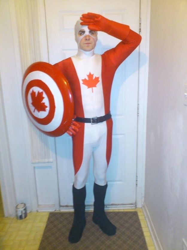 a man dressed up as captain america holding a shield in front of his face while standing next to a door