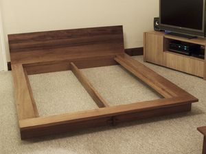 a bed frame made out of wood with a tv on the side and entertainment center behind it