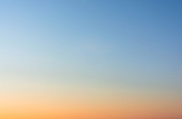 two people are standing on the beach watching the sun go down over the ocean and one person is flying a kite