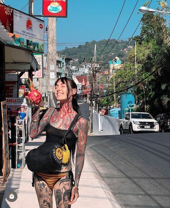 a woman with tattoos is walking down the street