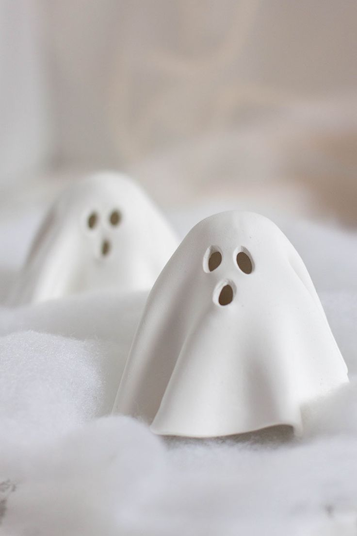 two white ghost figurines are sitting in the snow