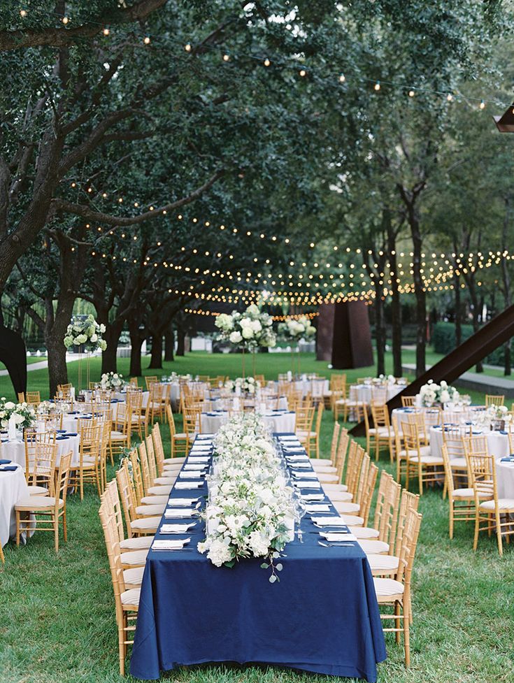 an outdoor wedding reception setup with blue table cloths and white flowers on the tables