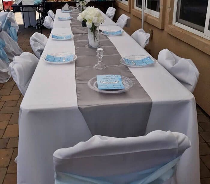 a long table set up with blue and white linens for a wedding or special event