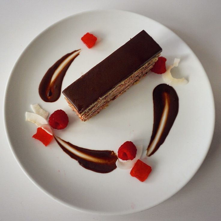 a white plate topped with a piece of cake covered in chocolate and candy toppings