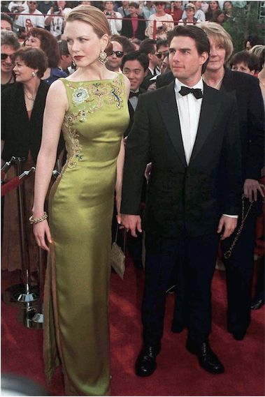 a man in a tuxedo standing next to a woman on a red carpet