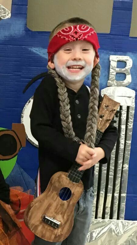 a young boy with long braids holding a ukulele