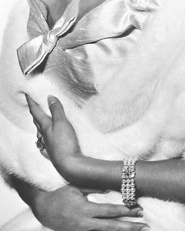 a black and white photo of a woman's hands holding a fur stoler