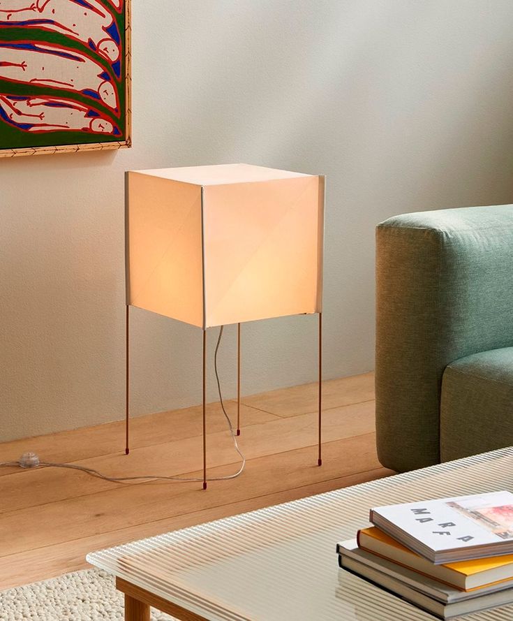 a living room with a couch, table lamp and painting on the wall behind it