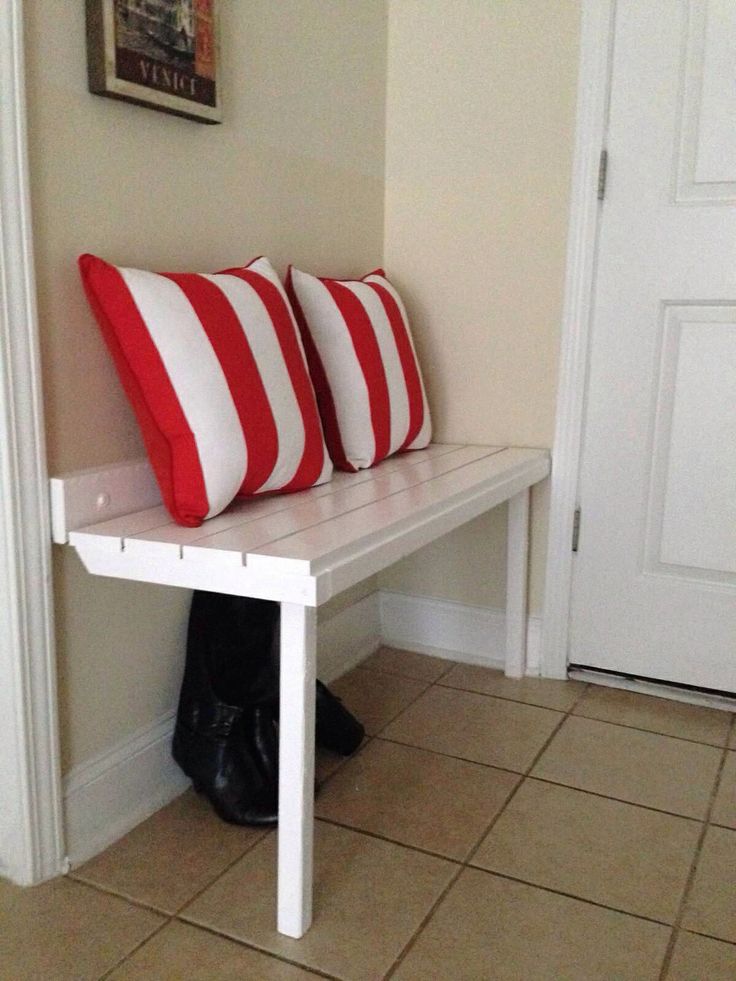 two red and white pillows sitting on top of a bench in front of a door