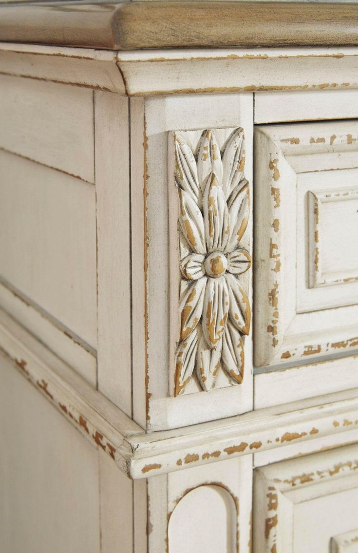 an antique white painted dresser with gold accents