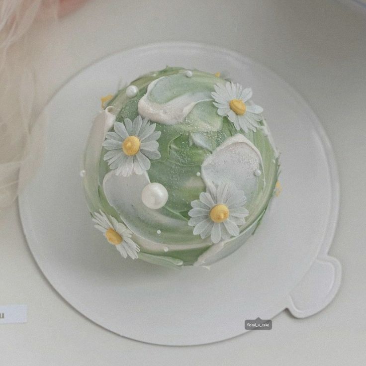 there is a green cake with white flowers on it