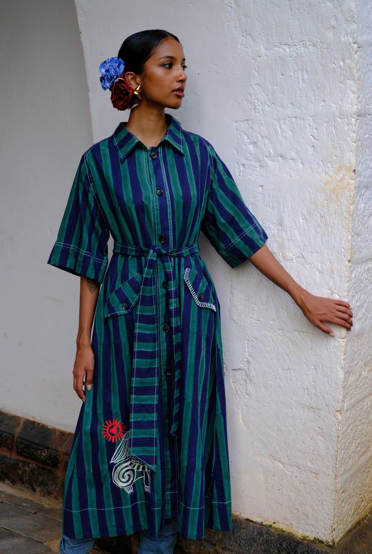 Did someone say chic? Our Javitri dress has an oversized, shirt-style silhouette and a tie up belt to cinch in your waist. It has a structured vibe with its boxy sleeves,and quirky embroidery details. We believe you have a right to know how this product was made. 3.5 metres of south Indian mangalgiri cotton fabric sourced from Jaipur has been used for this piece. Hand printed by our artisans in Jaipur, manufactured in our workshop at Pune, India. This product is hand-printed in Jaipur, India using techniques of traditional hand block printing. Subtle variations in patterns are natural to this process. We believe this makes each creation unique and charming. If you wish to have the length of the garment altered, please mention your request in the special instructions section at checkout, wi Cotton Collared Shirt Dress With Tie Waist, Collared Cotton Shirt Dress With Tie Waist, Cotton Dresses With Belted Cuffs, Cotton Collared Belted Dress, Collared Cotton Belted Dress, Belted Cotton Collared Dress, Cotton Shirt Dress With Belted Cuffs, Summer Cotton Shirt Dress With Belted Cuffs, Blue Cotton Belted Shirt Dress