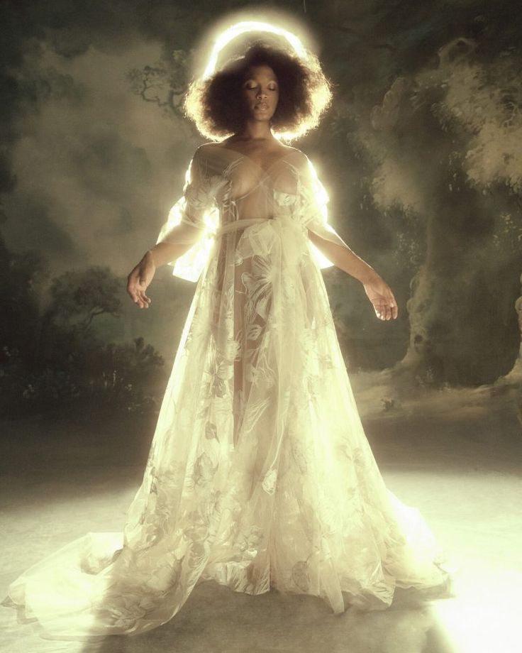 a woman in a white dress with an angel halo on her head and hands behind her back