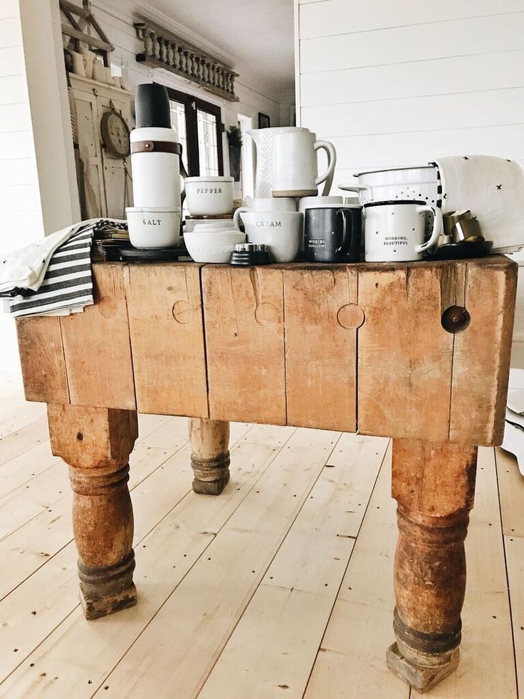 a wooden table topped with lots of coffee mugs and cups on top of it