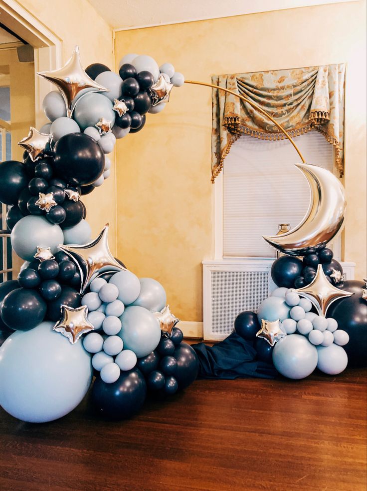 an arch made out of balloons in the shape of stars and crescents on a wooden floor