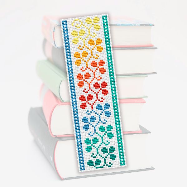 a cross stitch bookmark on top of three books