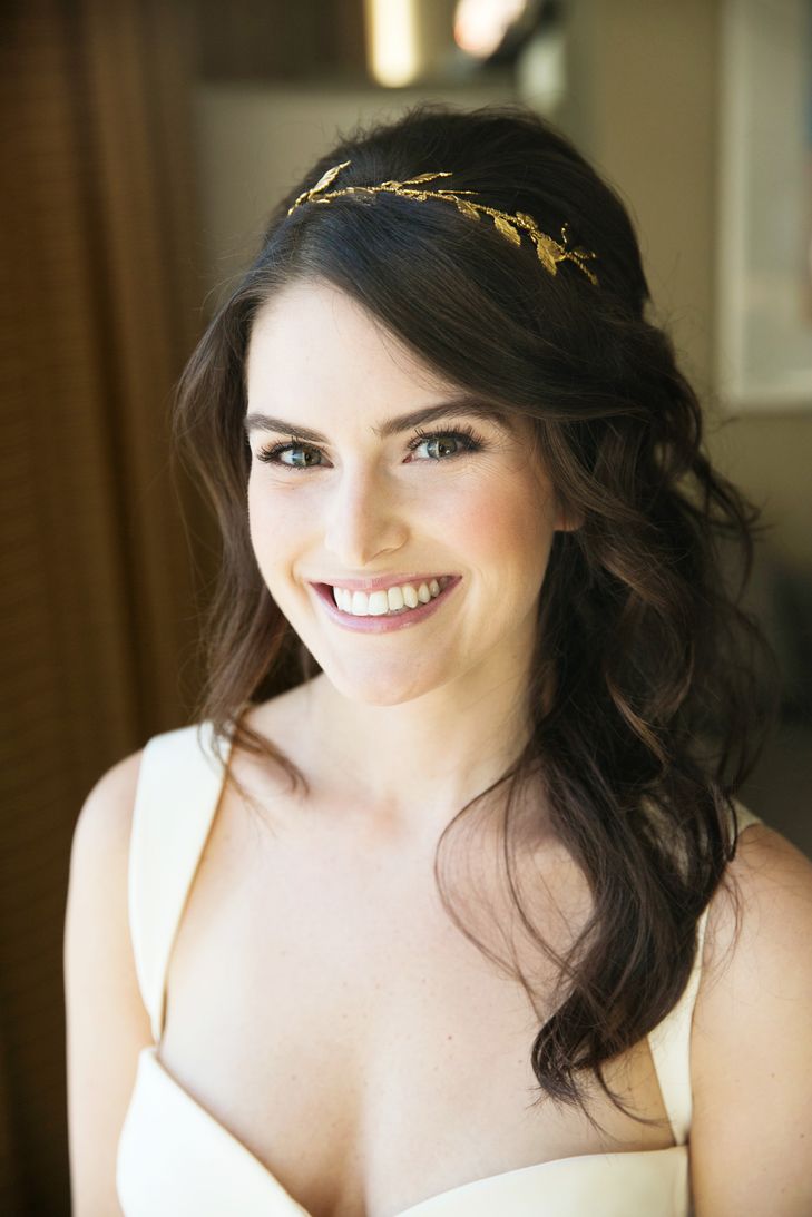 a smiling woman wearing a gold headband