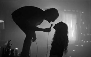 two people standing in front of a purple light