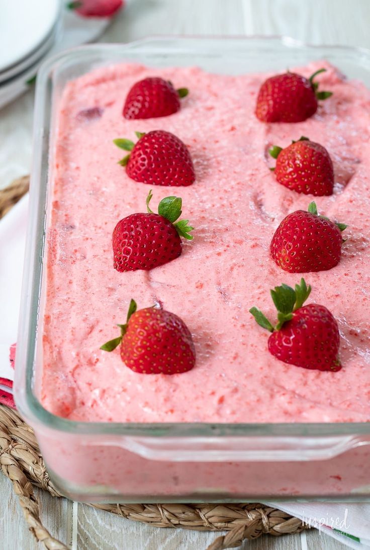 a close up of a dessert with strawberries on top in a glass dish,