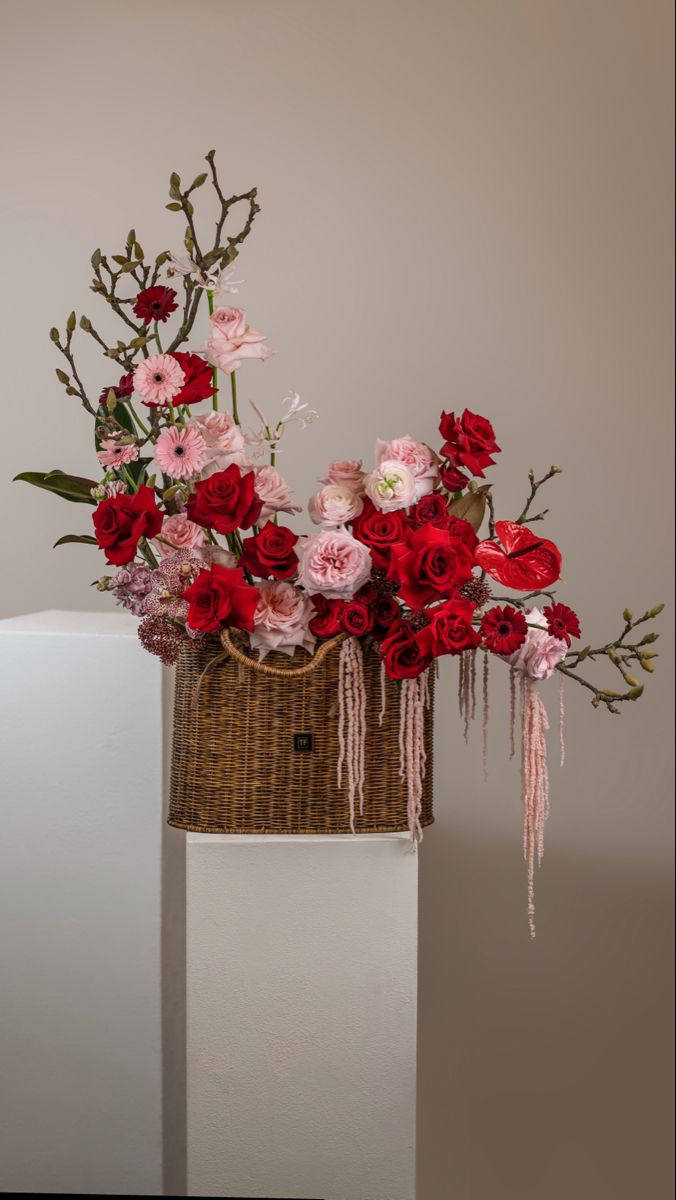 red and pink flowers are in a basket