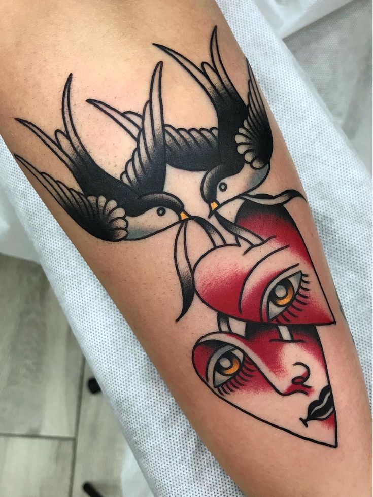 a couple of birds sitting on top of each other next to a red heart tattoo