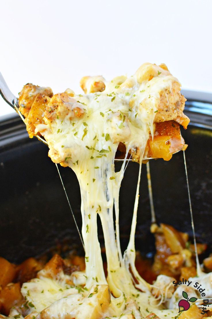 a close up of a piece of pizza being lifted from a crock pot