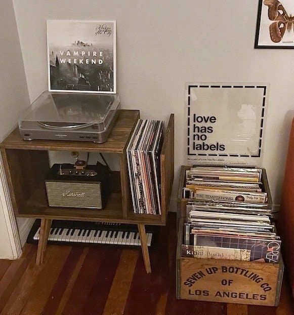 a record player sitting on top of a wooden table next to a pile of records