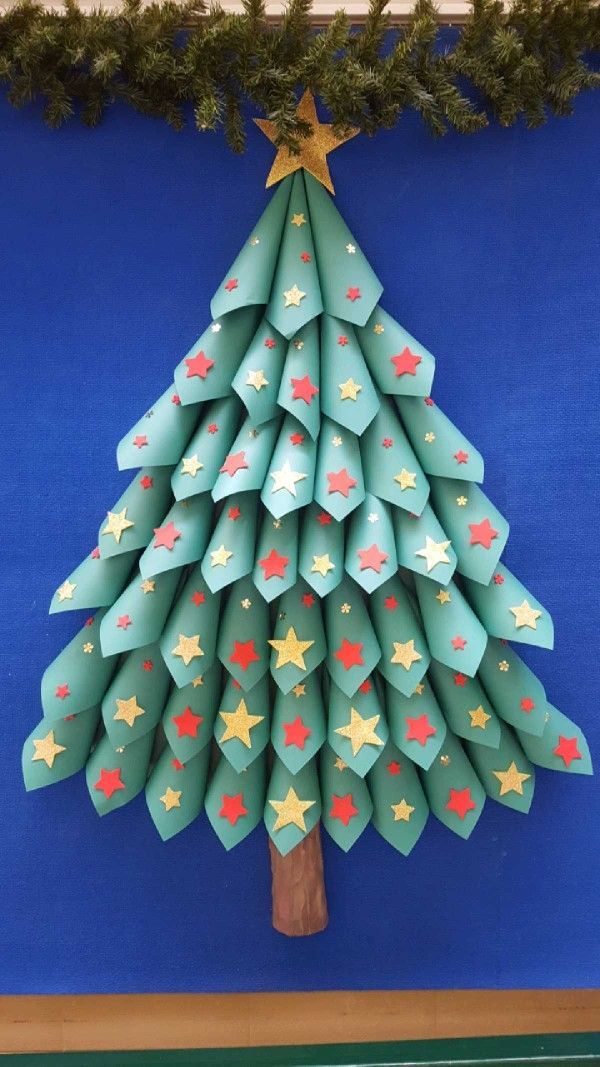 an origami christmas tree on a blue wall