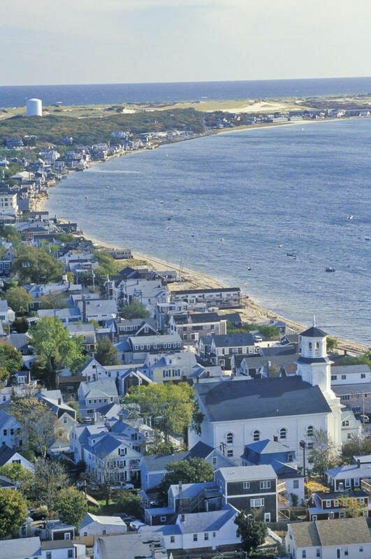 an aerial view of a town by the ocean with houses and water in the background