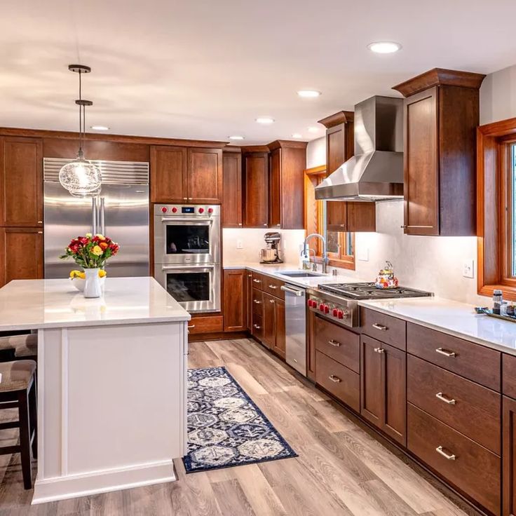 a large kitchen with wooden cabinets and white counter tops, an island in the middle