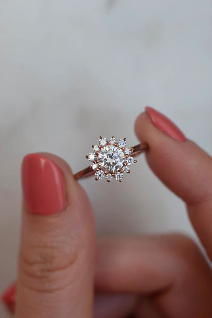 a woman's hand holding an engagement ring with a diamond center on the band