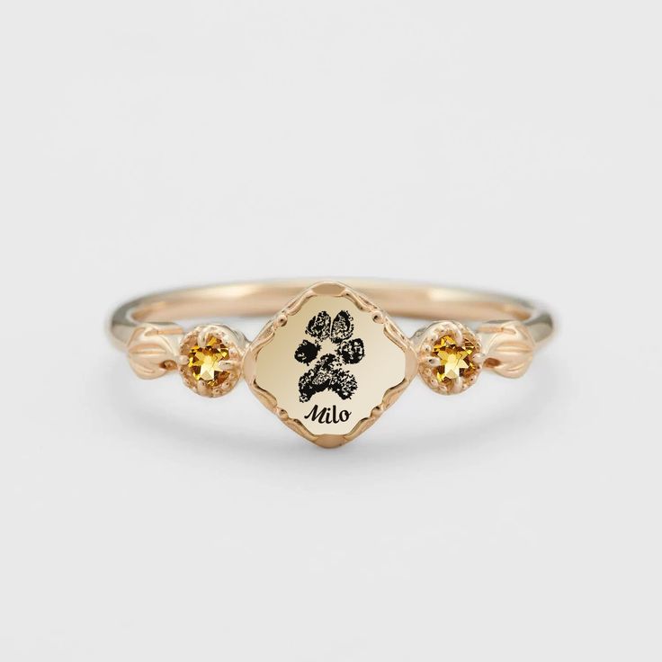 a gold ring with the word mom engraved on it and two small yellow sapphires