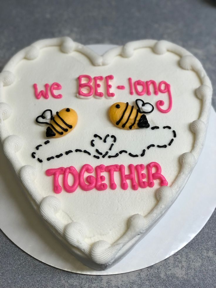 a cake shaped like a heart with two bees on it that says we bee - long together