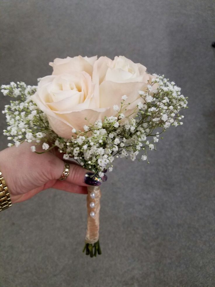 a person holding a bouquet of white flowers in their hand with pearls on the wrist