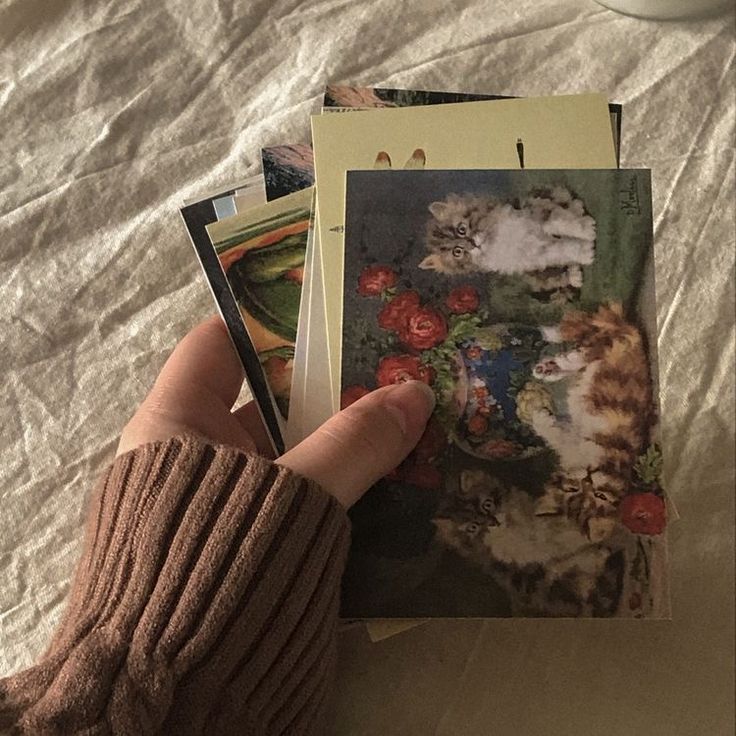 a person holding several cards in their hand on top of a white sheet covered bed