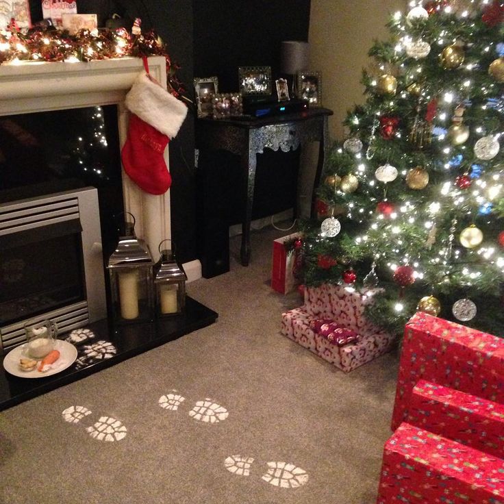 a living room with a christmas tree and presents on the floor next to a fire place