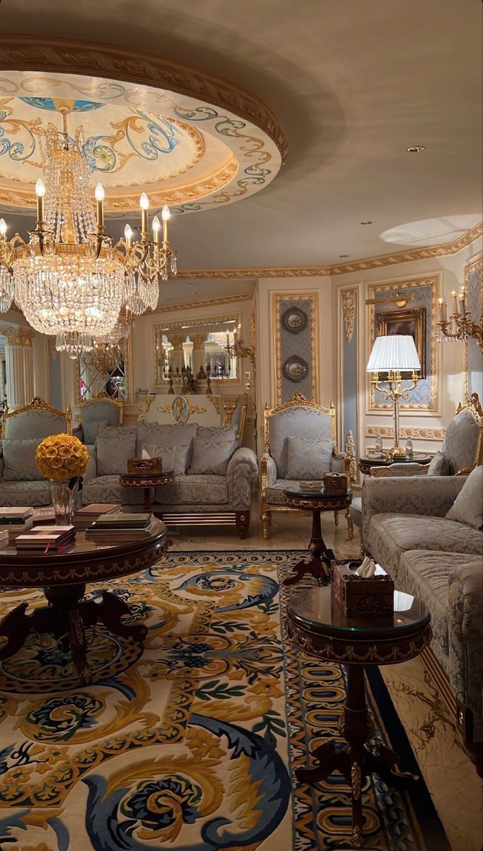 a fancy living room with chandelier, couches and tables in it's center