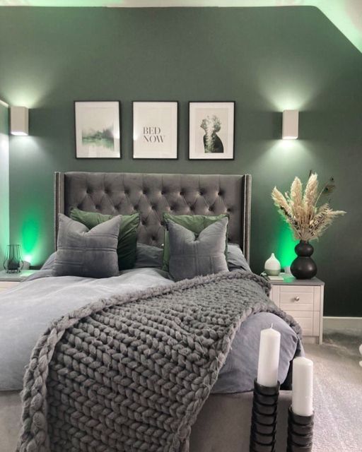 a bedroom with green walls and pictures on the wall above the bed, along with candles