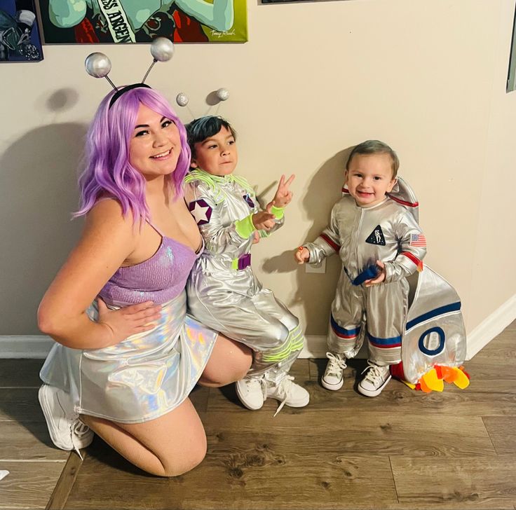 a woman and two children dressed up as buzz lightyears, alien man and rocketman