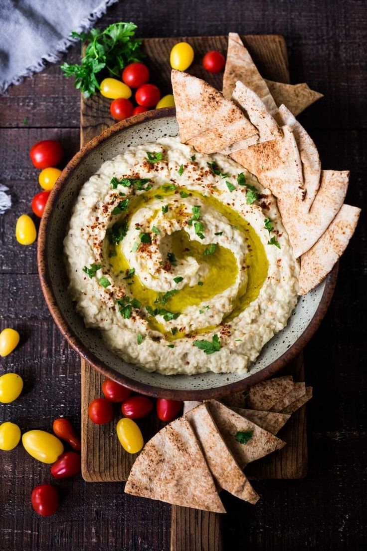 hummus in a bowl surrounded by corn, tomatoes and tortilla chips