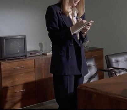 a woman is standing in an office looking at something on her tabletop while holding a folder