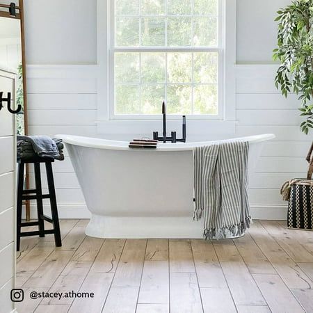 a white bath tub sitting under a window next to a wooden table and stools