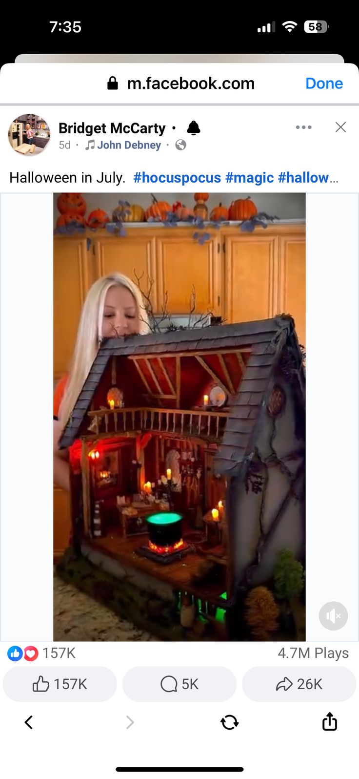 a woman holding up a fake doll house in front of her face with candles on it