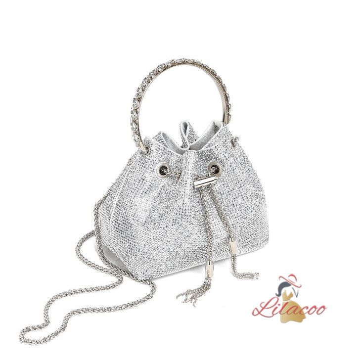 Indulge in the luxurious appeal of this sparkling silver handbag, a perfect blend of glamour and practicality. The exterior is adorned with countless tiny crystals, creating a shimmering effect that will undoubtedly capture attention at any event. The bag features a drawstring closure, adding a touch of modernity to its classic bucket bag design. The silver-tone metal handle is not only stylish but also sturdy, ensuring easy and comfortable carrying. Additionally, it comes with a detachable silv Handheld Silver Evening Bag With Chain Strap, Silver Handheld Evening Bag With Chain Strap, Silver Evening Bag With Chain Strap For Events, Elegant Silver Bag With Chain Strap, Elegant Metallic Evening Bag, Elegant Bucket Bag With Rhinestones, Party Shoulder Bag With Silver-tone Hardware, Bucket Shape, Elegant Metallic Bag With Chain Strap, Party Bucket Shoulder Bag With Silver-tone Hardware